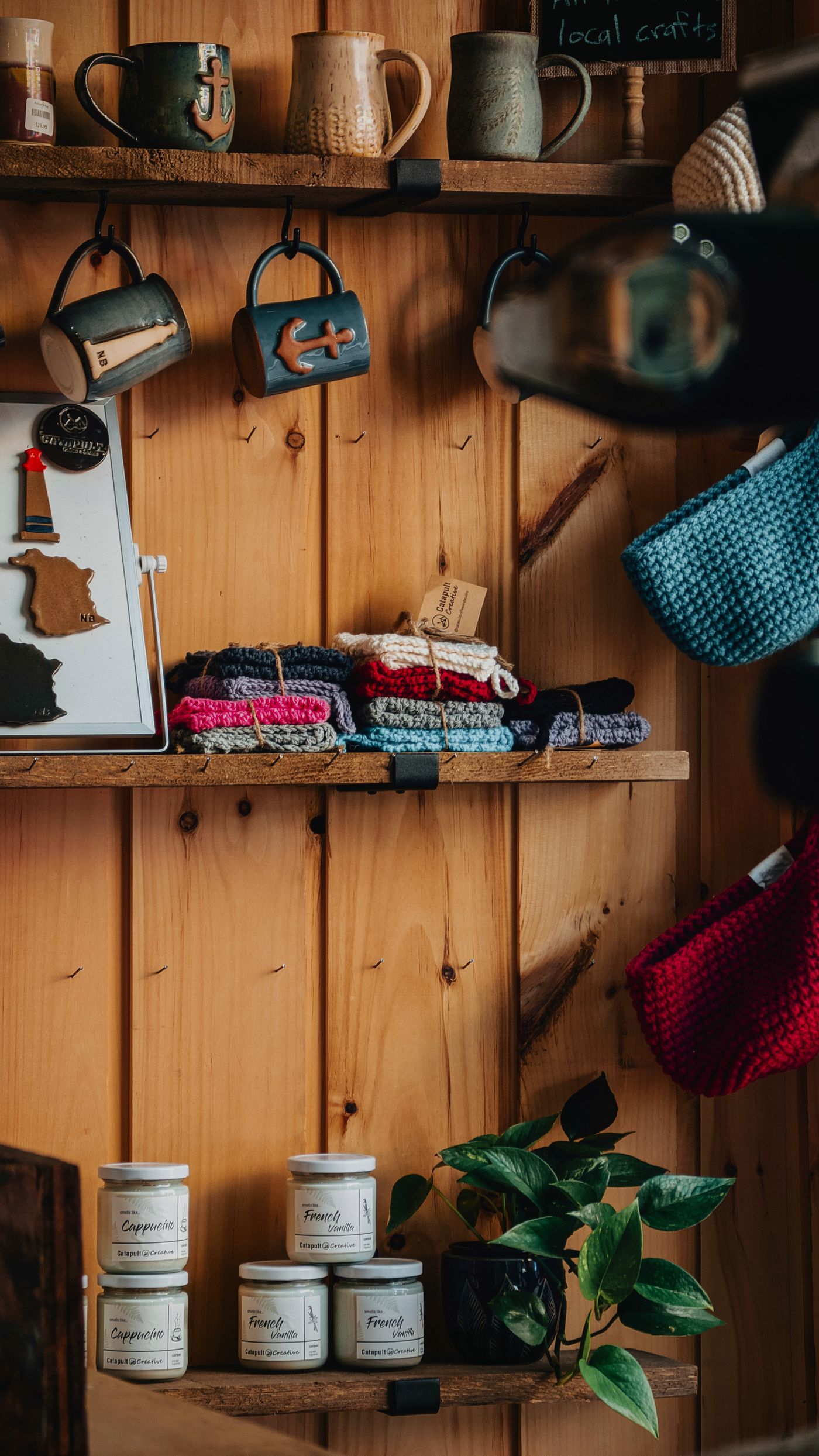Rustic wooden shelves of handmade mugs, knit goods and candles
