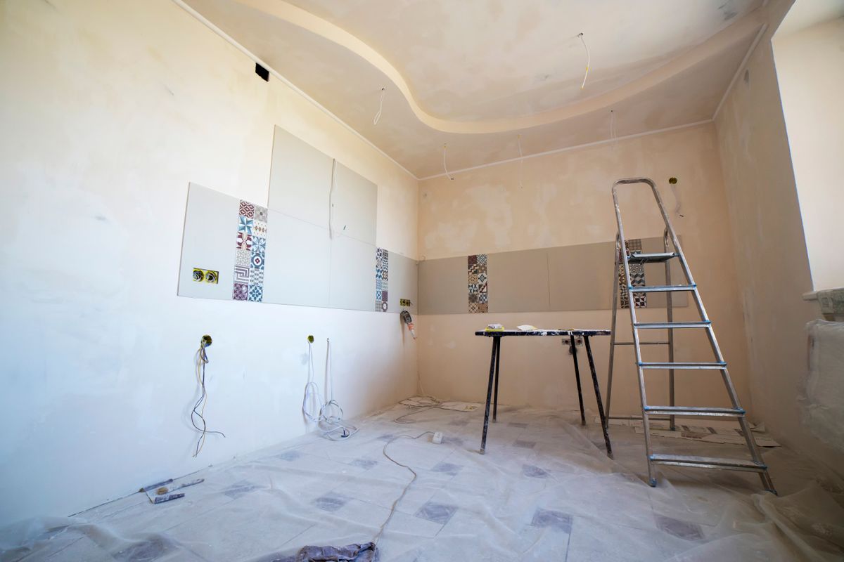 A room mid-renovation with skim-coated walls and a flat ceiling