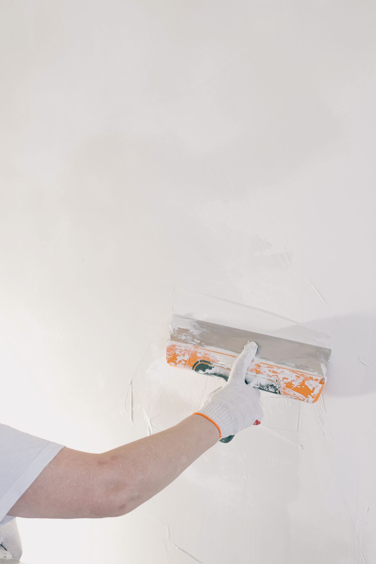 A wide trowel skimming a smooth coat across a wall