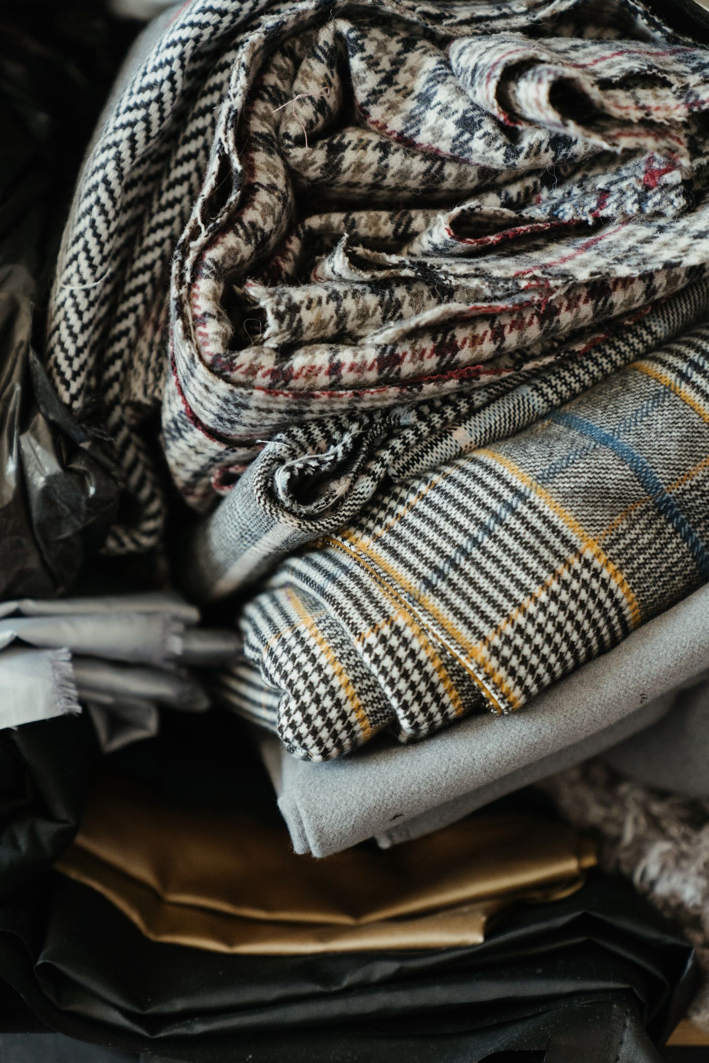 A folded stack of plaid, tweed and check designer fabrics