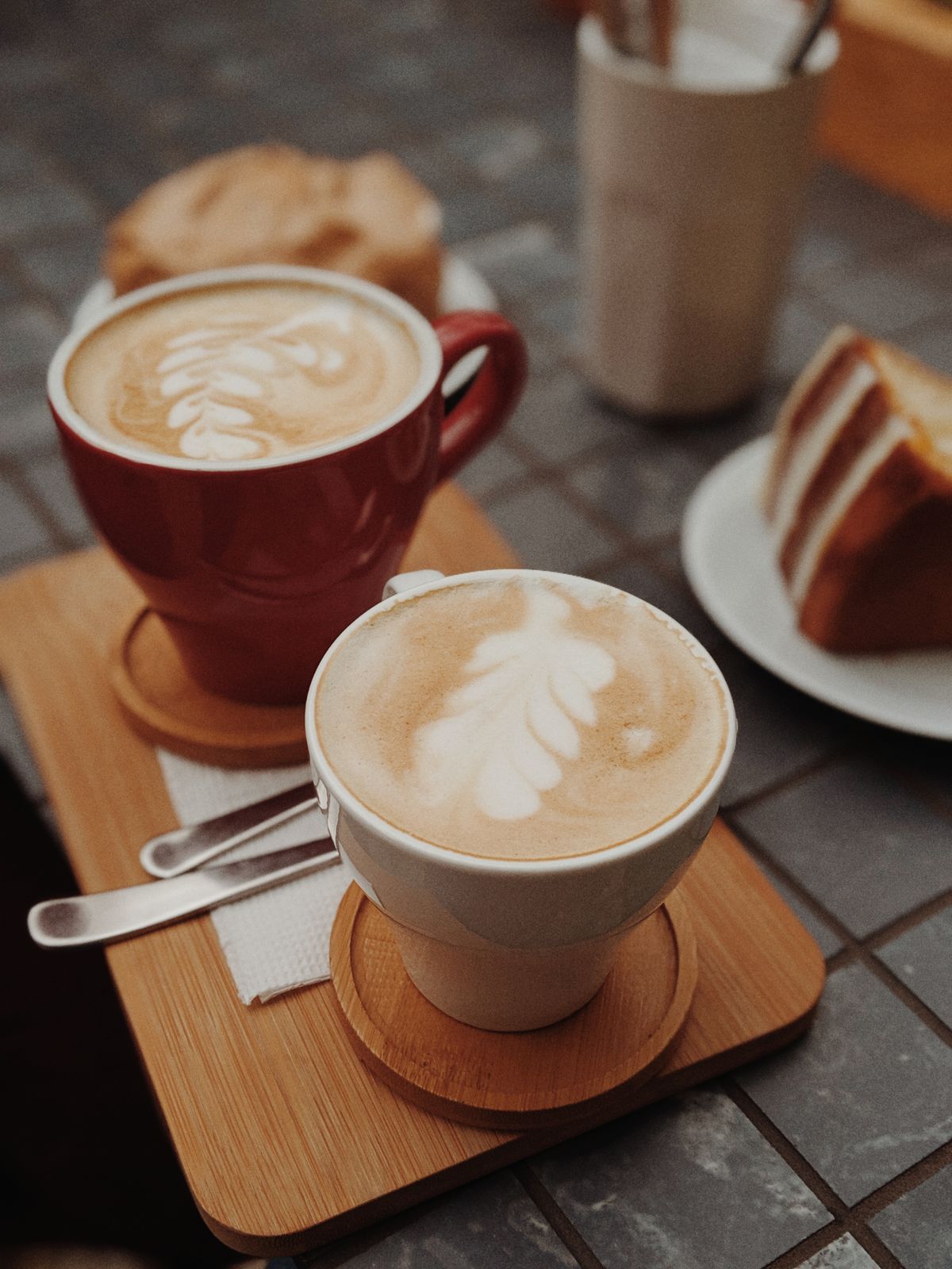 Two latte-art cups on a wooden board