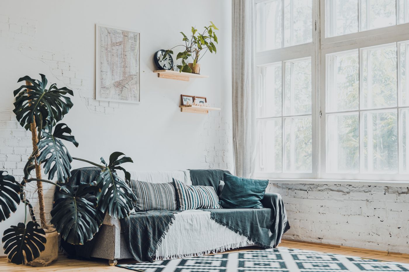 A bright studio room with monstera plants, soft couch and white brick walls