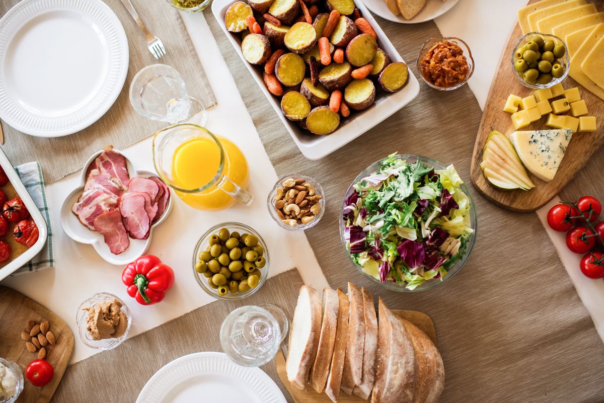 An antipasto spread of cured meats, olives, cheese and bread laid out on a wooden table