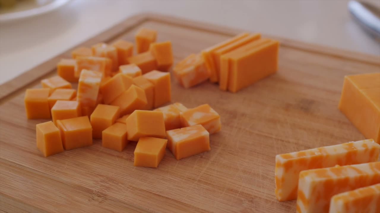 Slabs of cheese being cut on a wooden board at the deli counter