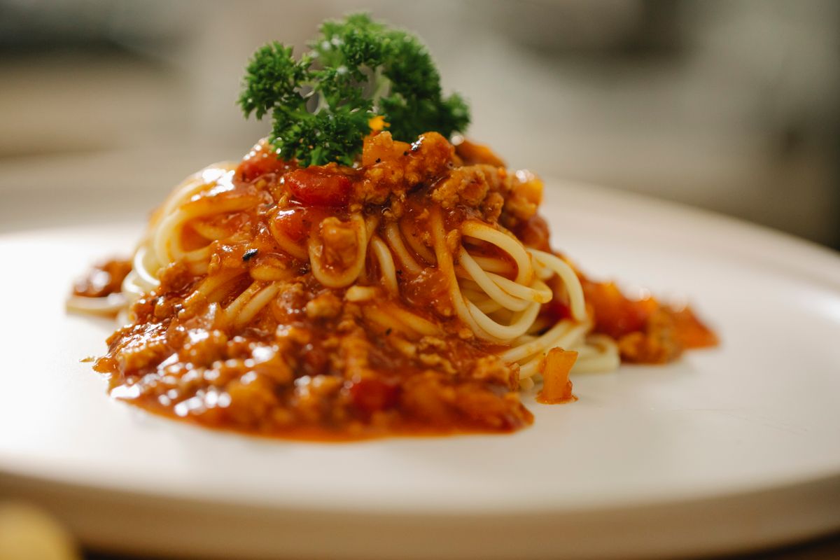 A plate of spaghetti in tomato sauce finished with parsley