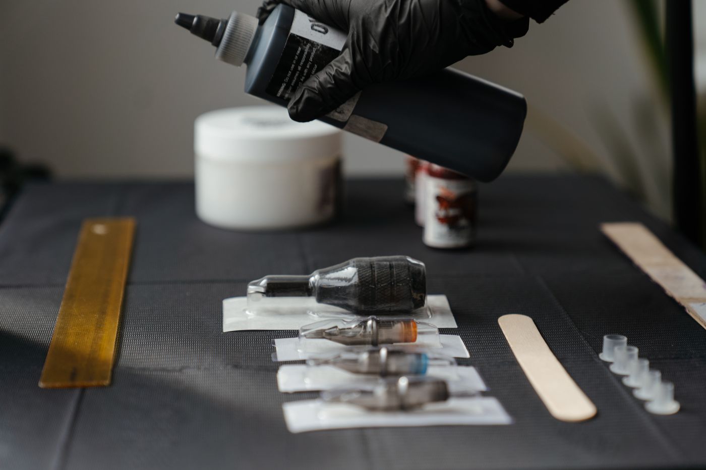A tattoo machine and wrapped tools laid out on a dark clean surface