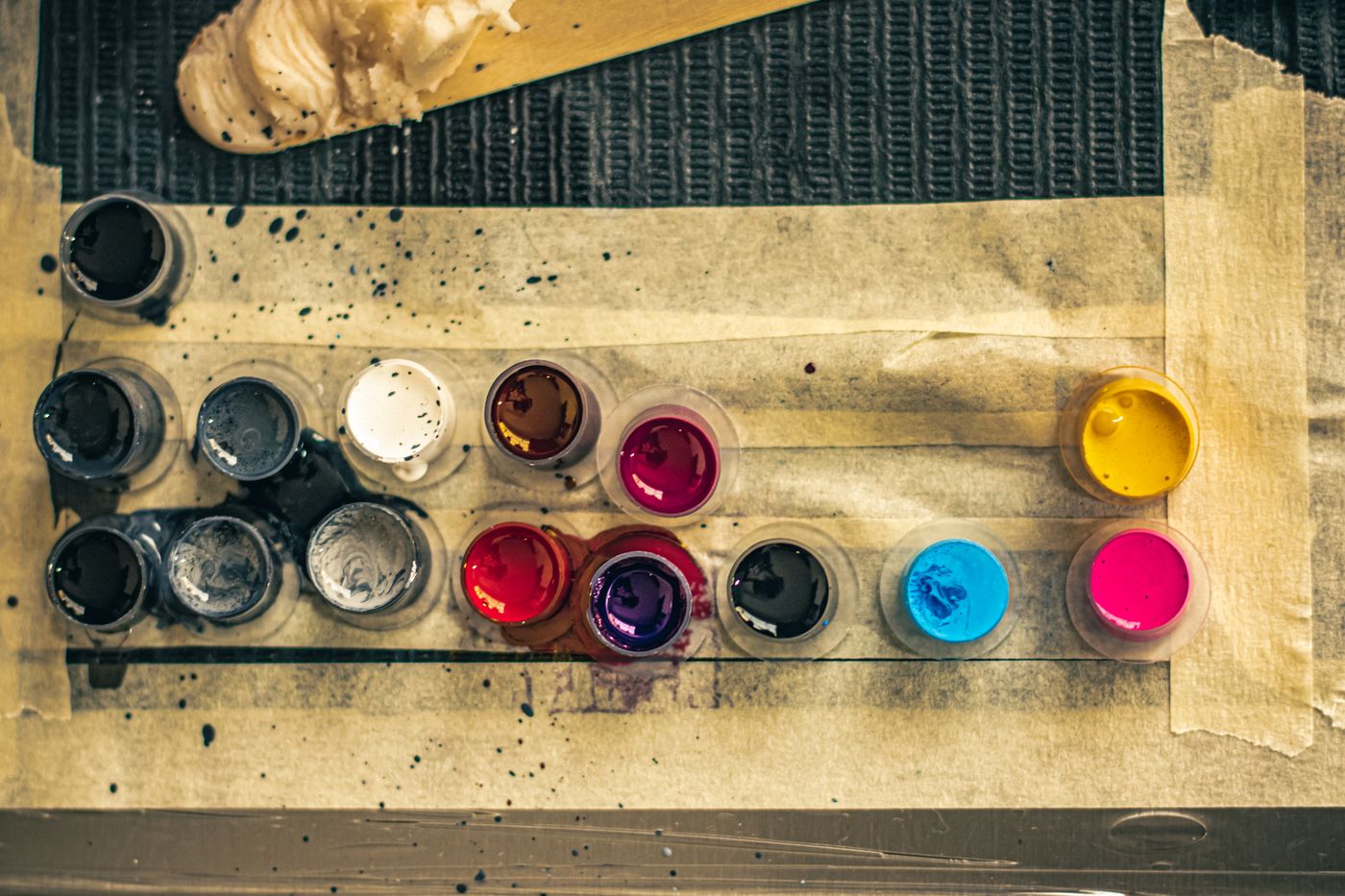 Caps of coloured tattoo ink arranged on a covered surface, seen from above
