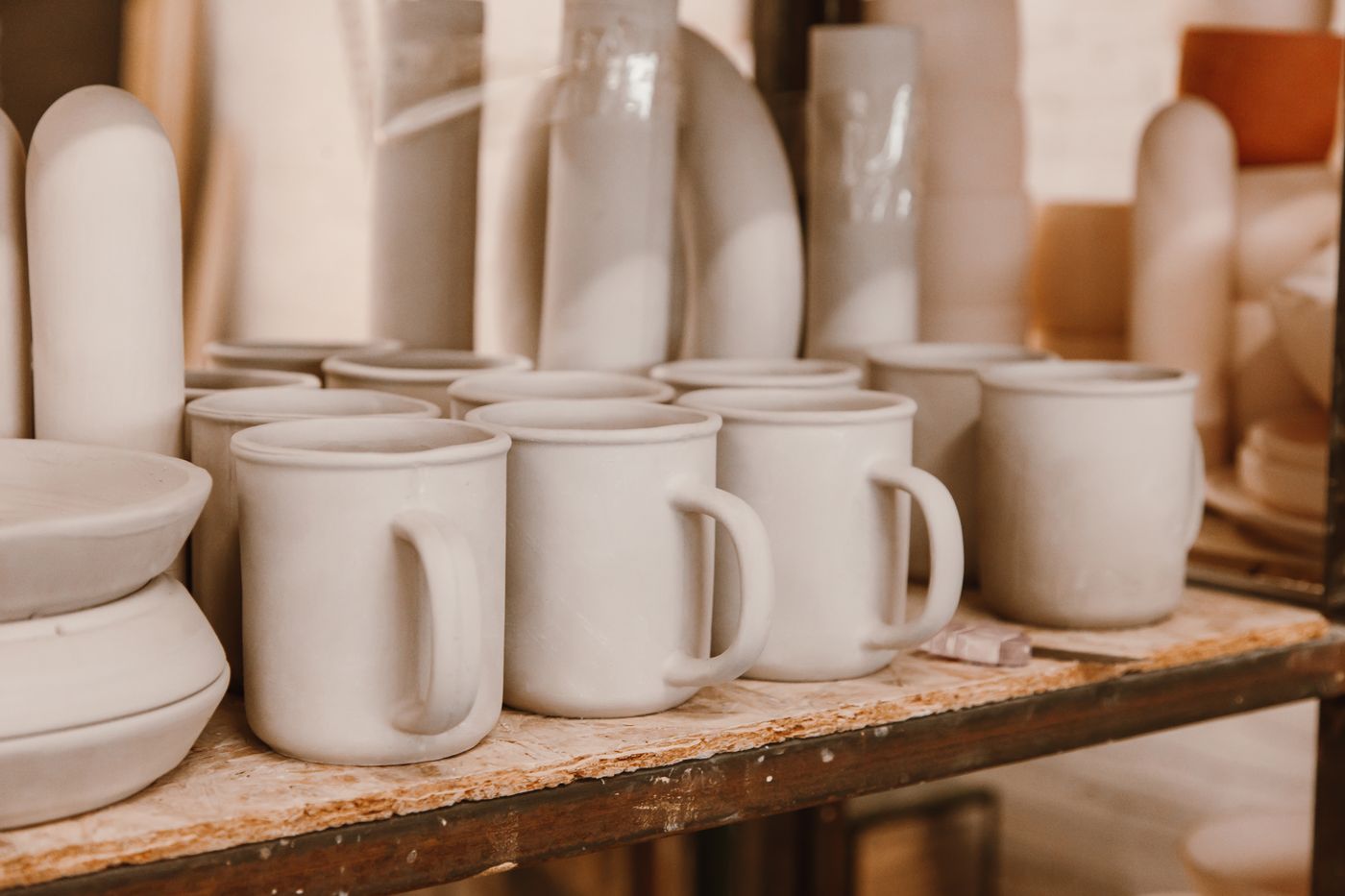 A row of unglazed greenware mugs