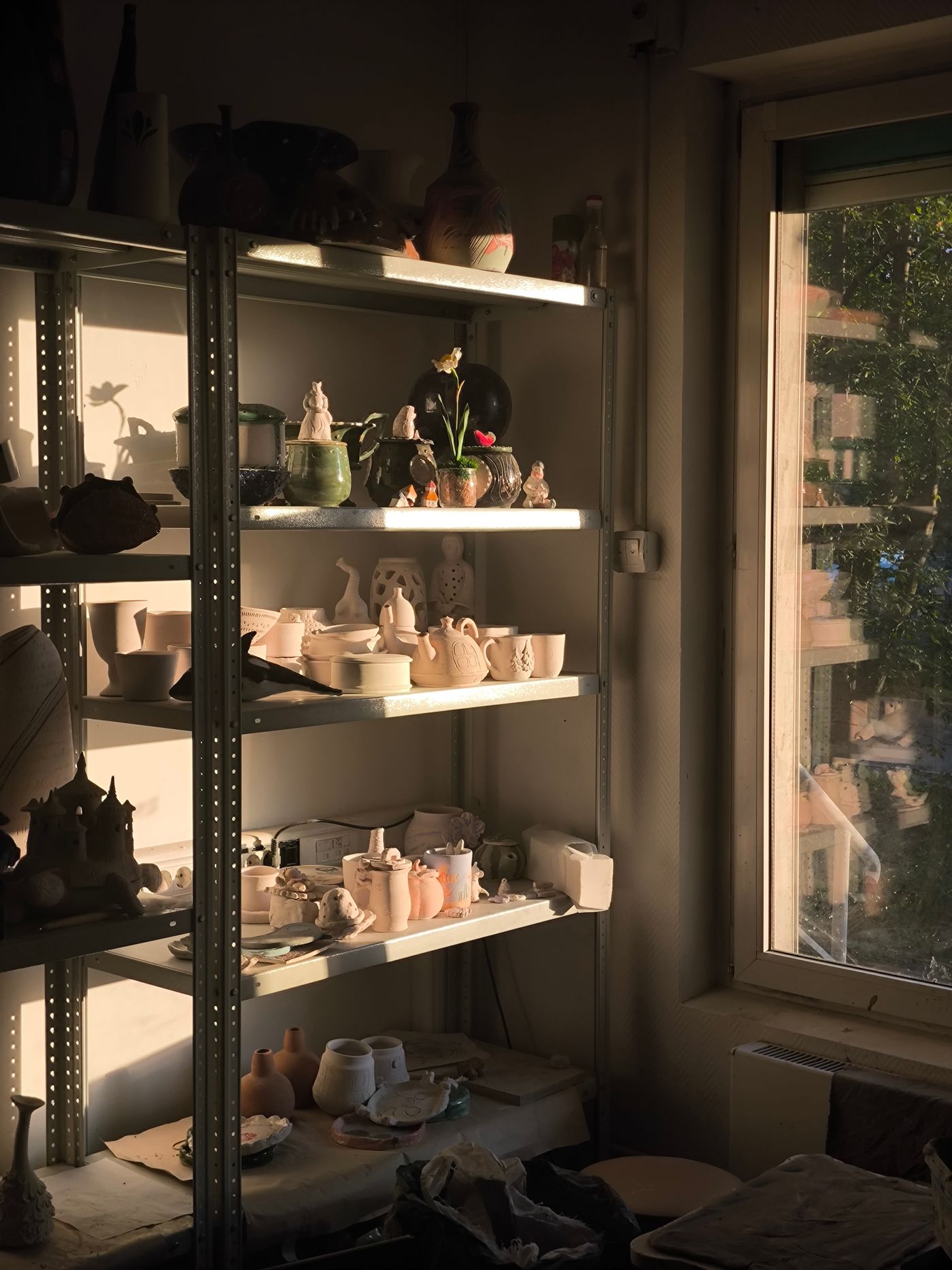 A sunlit pottery studio with shelves and tools