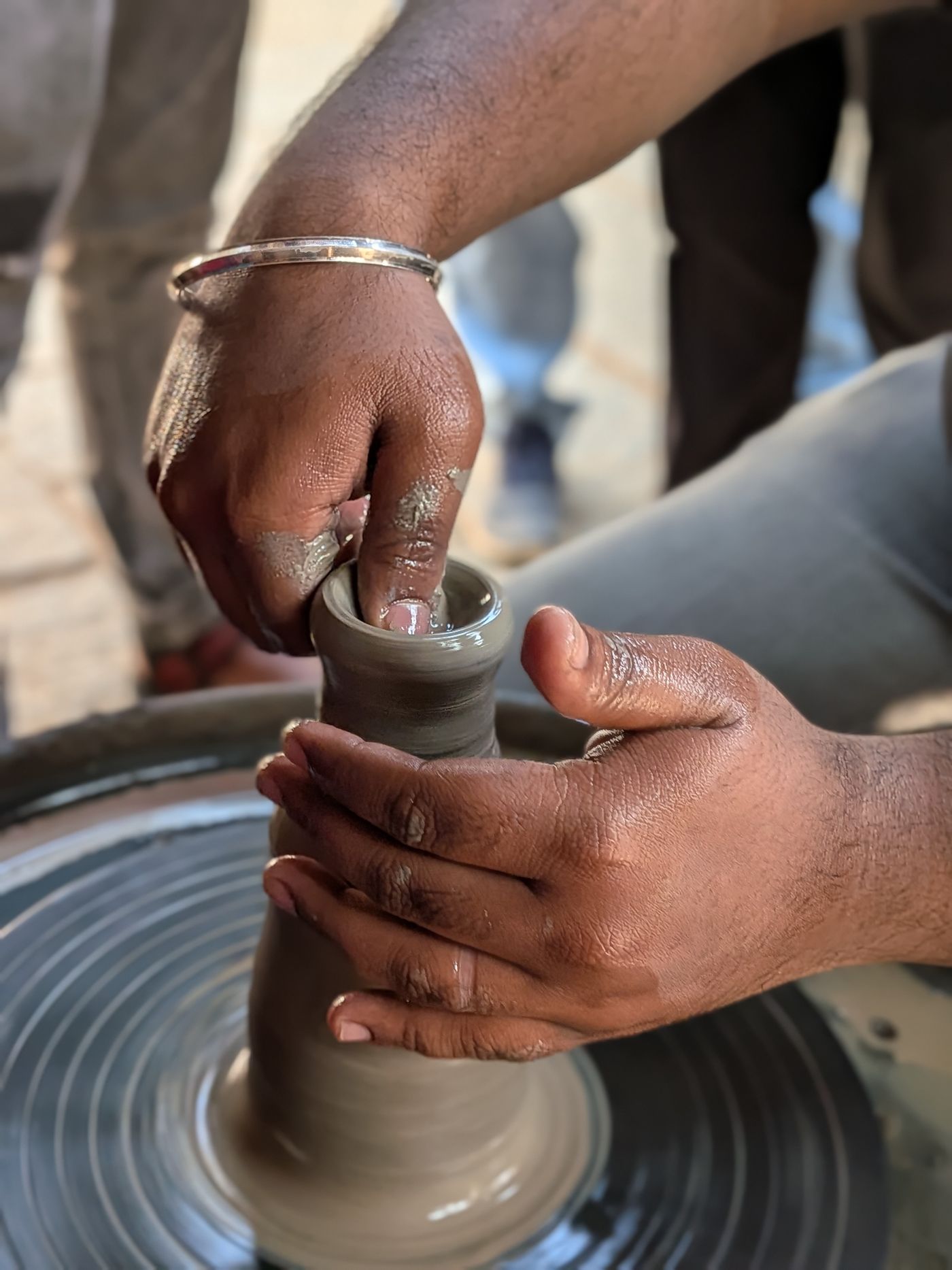 Hands centring clay on the pottery wheel