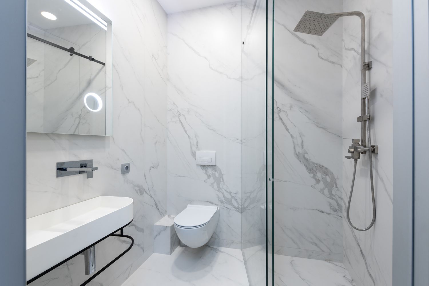Renovated bathroom with marble walls and walk-in shower