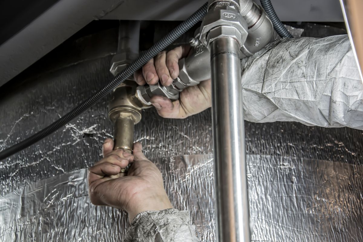 Hands fitting a brass valve to copper pipework