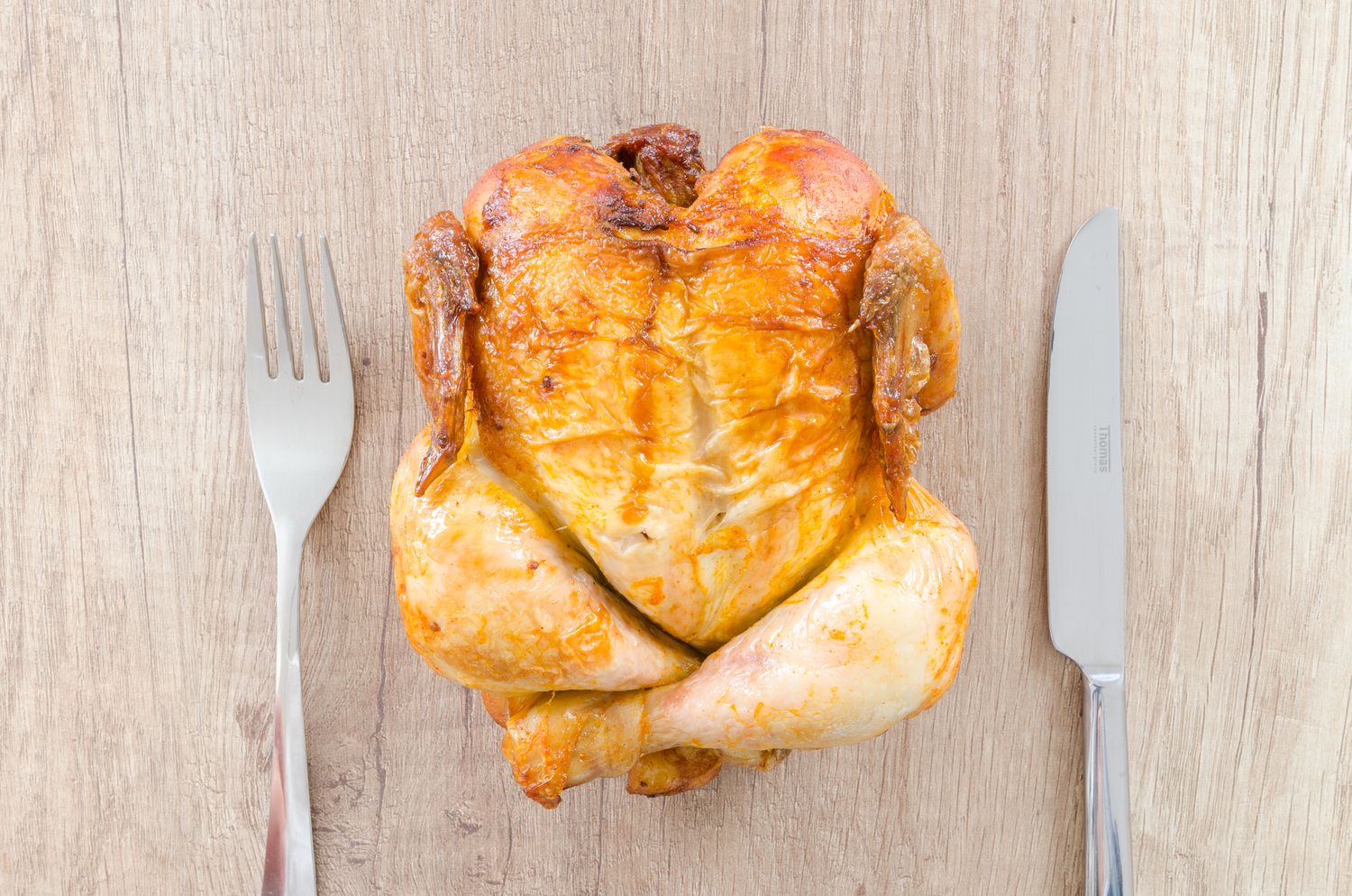 A whole roast chicken with a carving knife