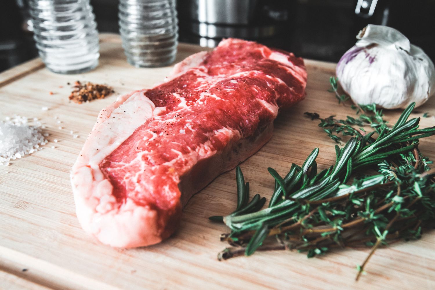 A raw striploin steak seasoned on a board