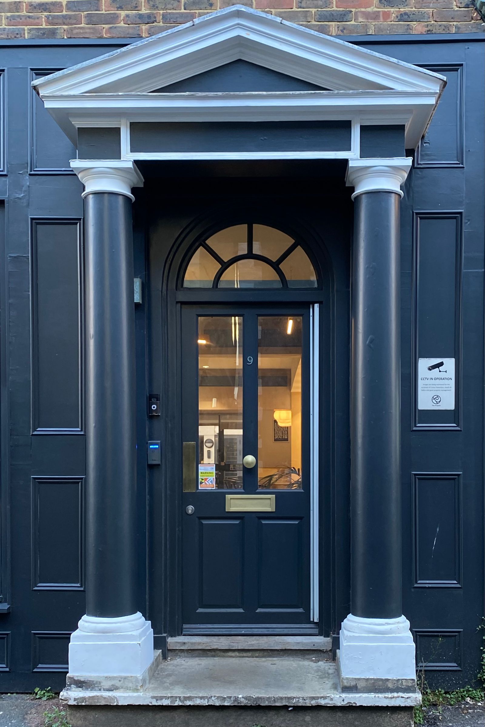 A navy entry door under a columned porch