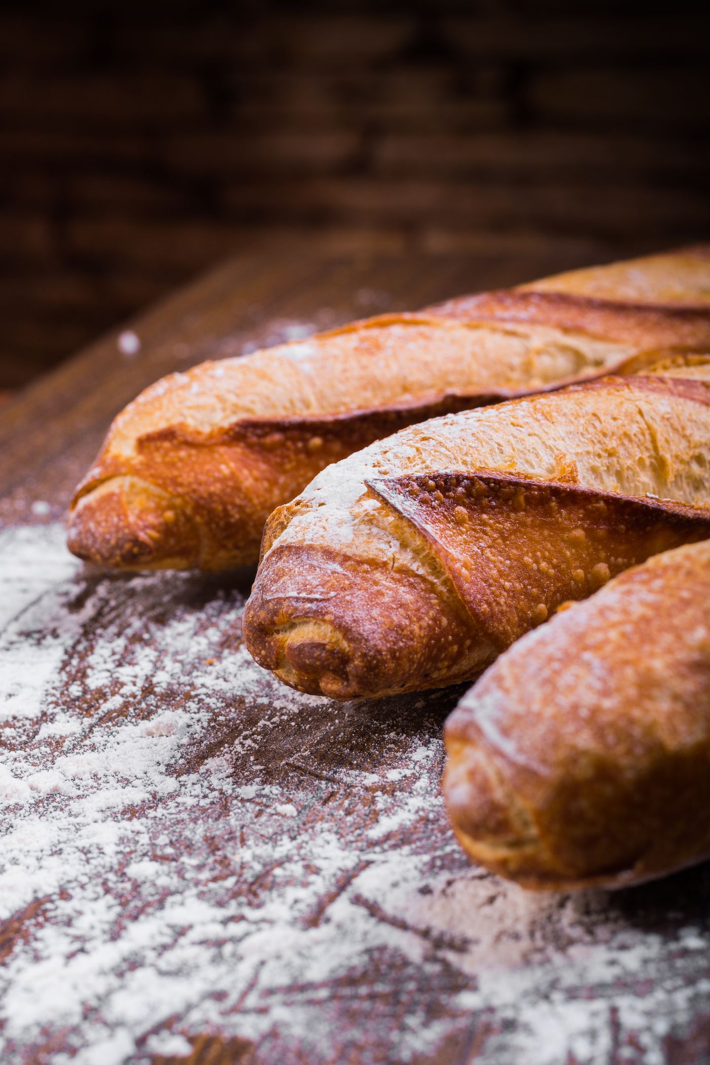 Crusty flour-dusted baguettes on a bench