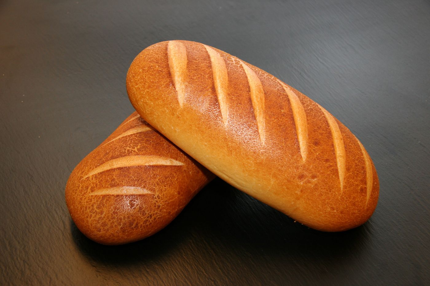 Two golden loaves on a dark surface