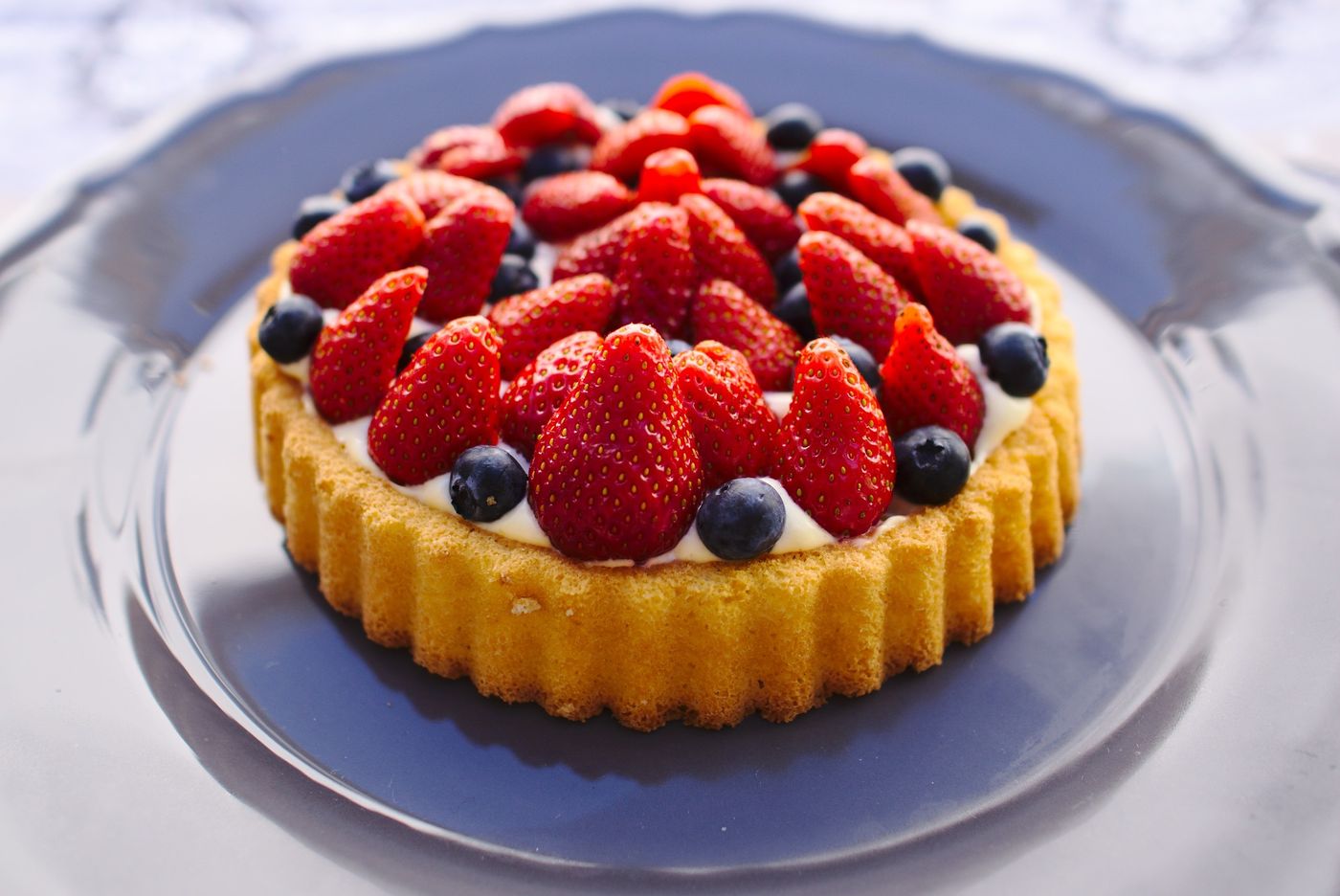 A strawberry-and-blueberry sponge tart on a plate