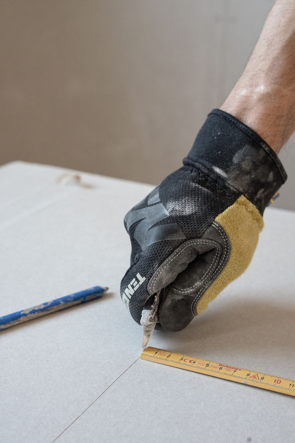 A gloved hand cutting plasterboard during the rebuild