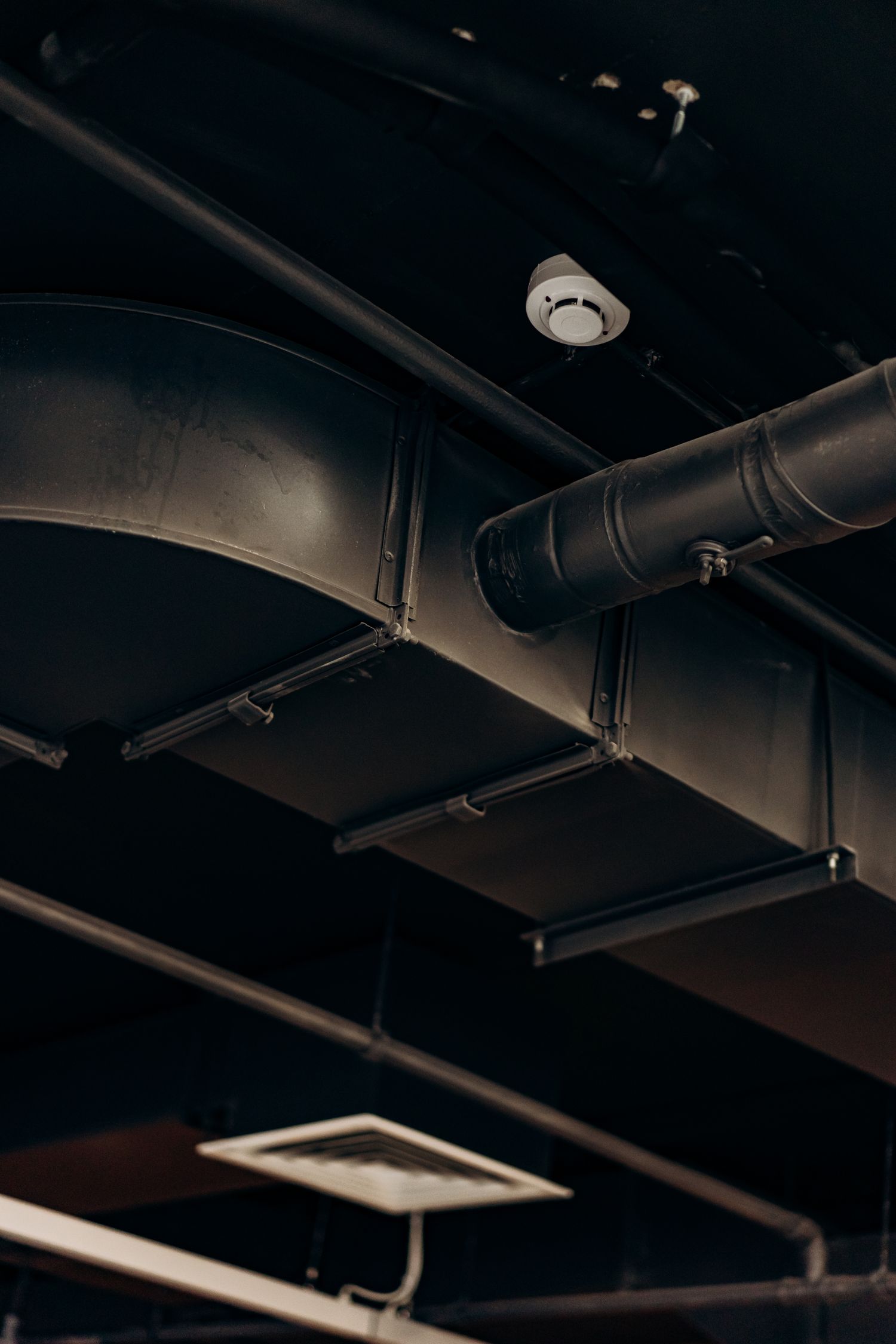 Dark industrial ductwork running across a ceiling