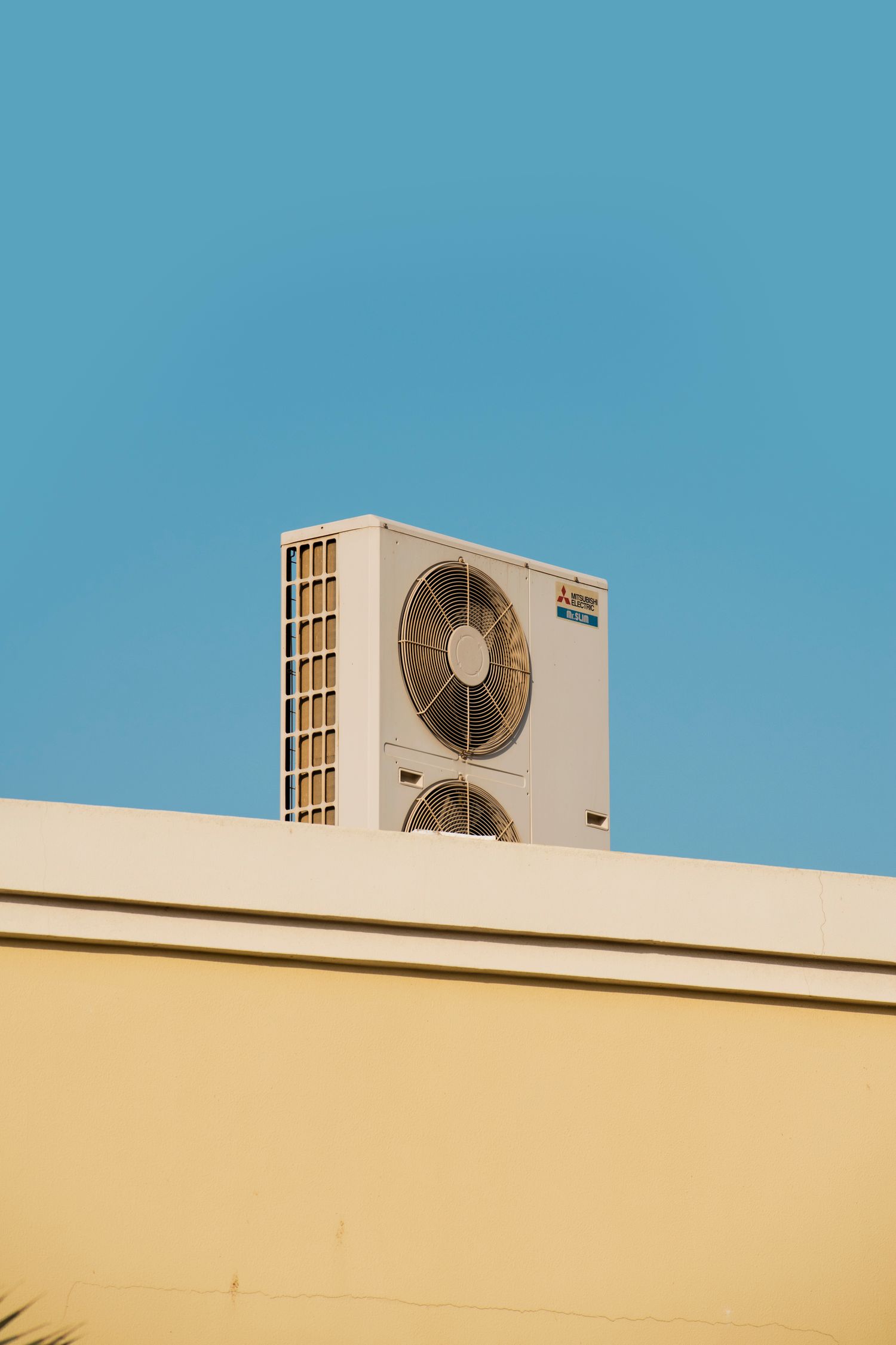 A single condenser unit on a rooftop against blue sky