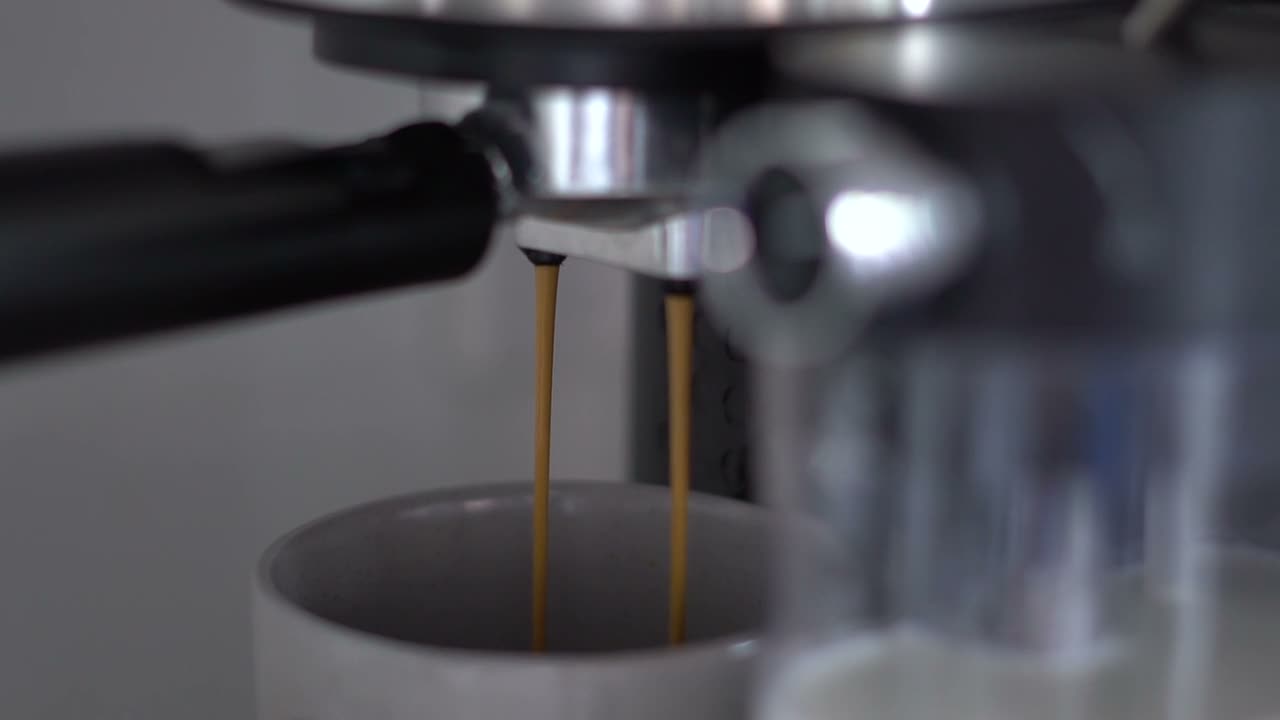 An espresso machine pouring into a white cup