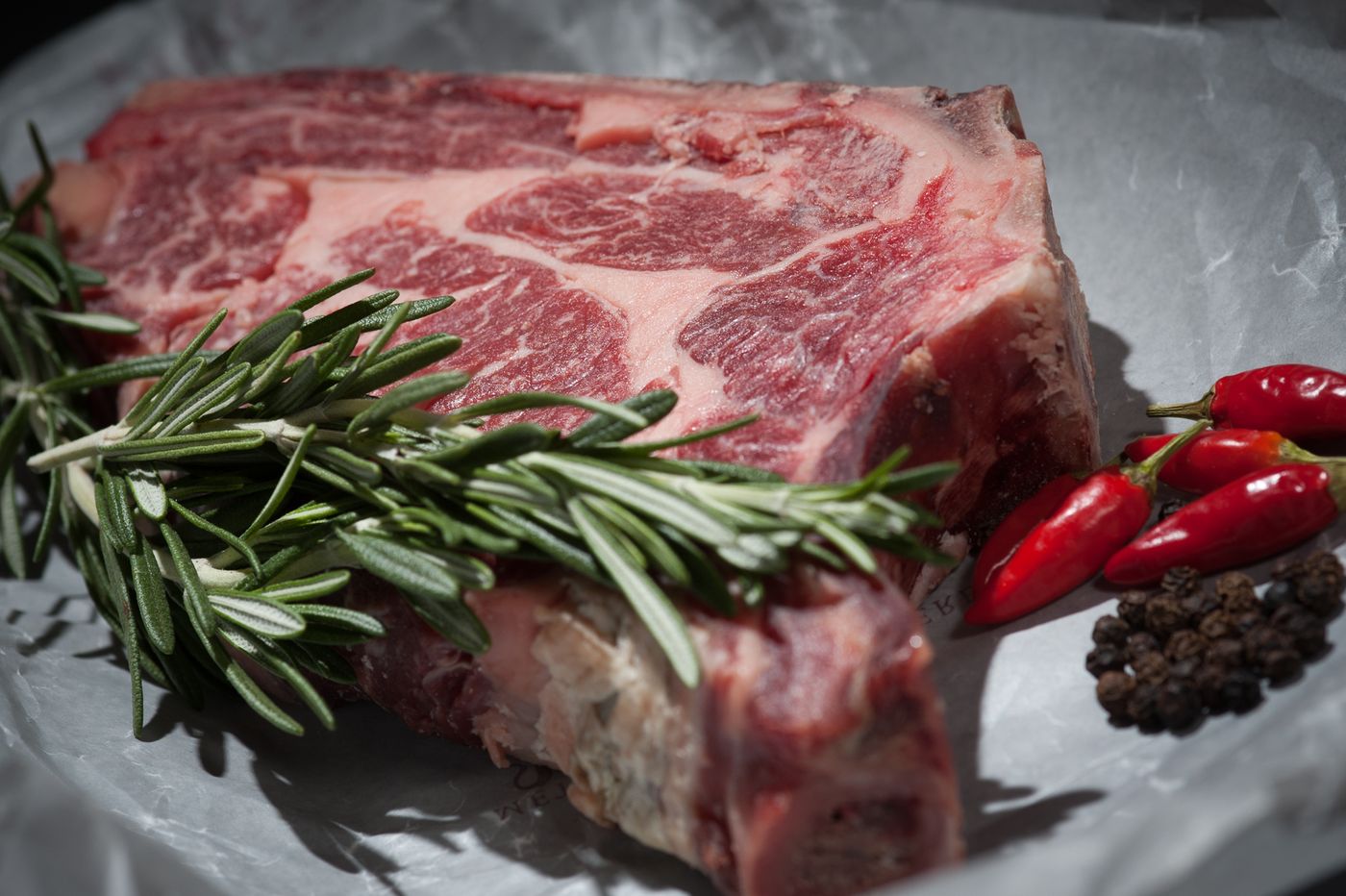 Marbled raw steak with rosemary on a board