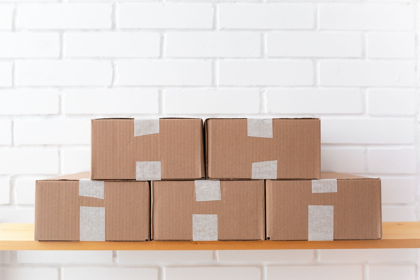 Neatly taped boxes on a shelf against a brick wall