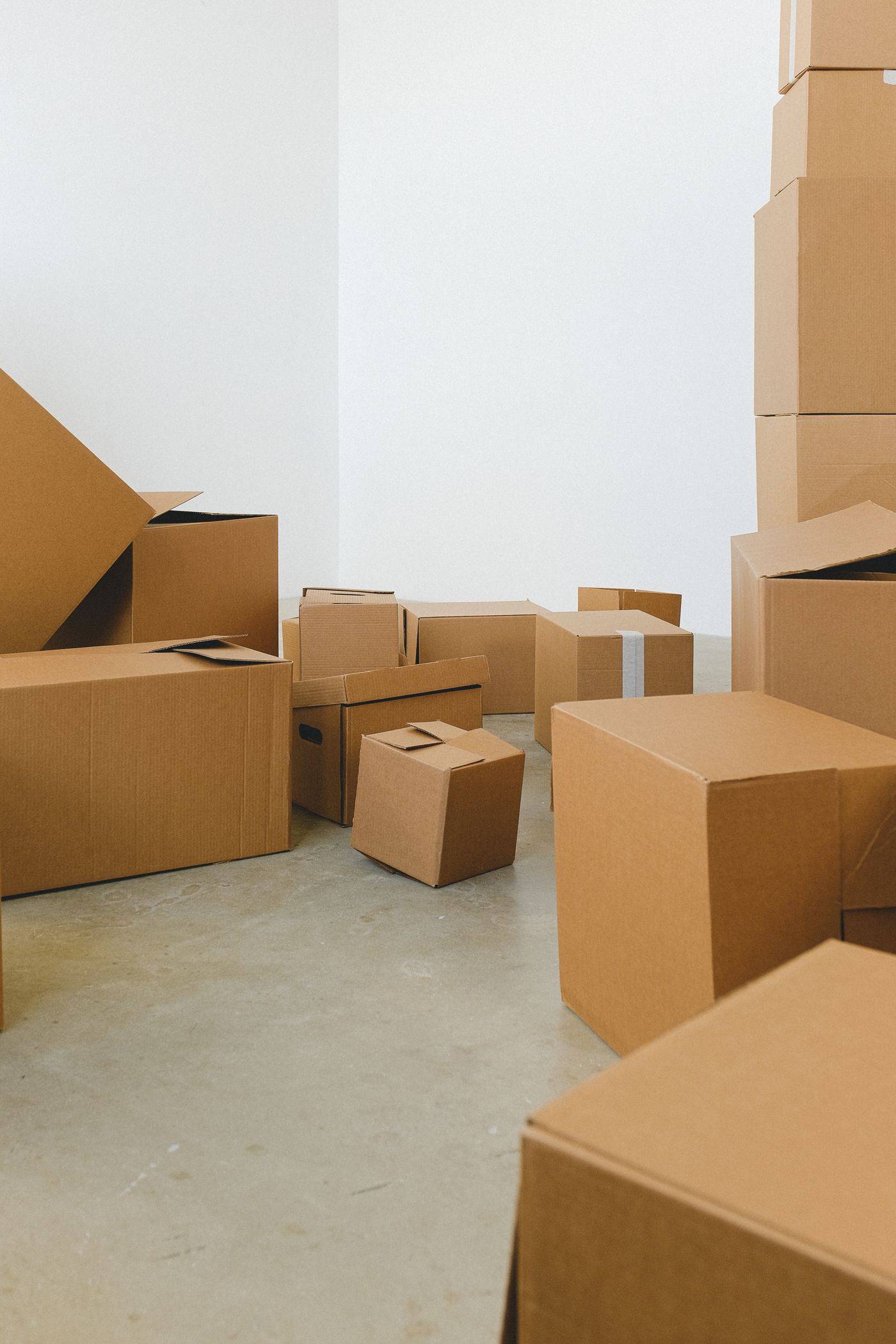 A pile of packed cardboard boxes on the floor of a new home