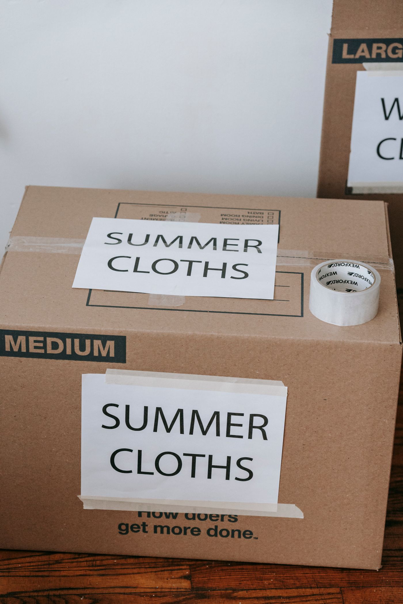A moving box with a hand-written content label and packing tape