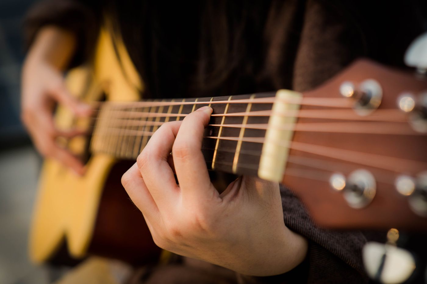 Hands playing an acoustic guitar at a small live-music night