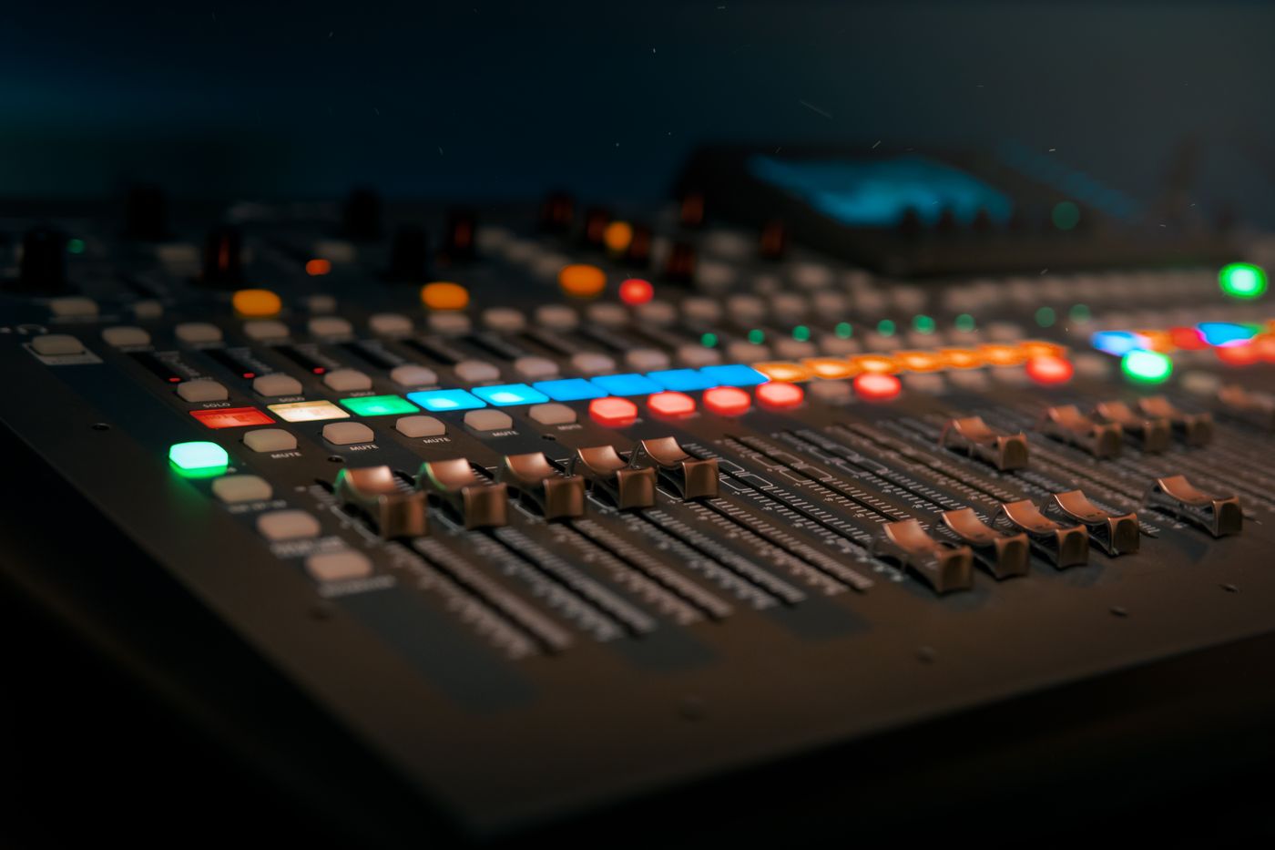 A live-sound mixing desk with colourful faders