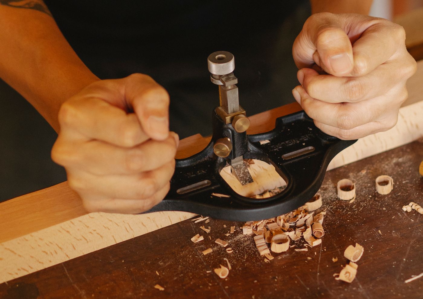 A hand plane shaving wood at a repair bench