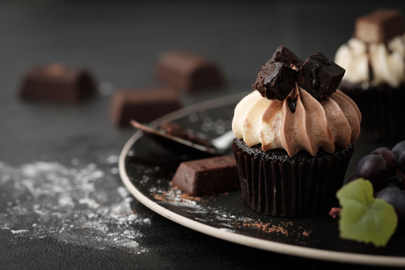 Buttercream-topped chocolate cupcake on a dark plate