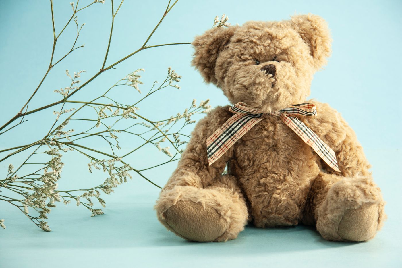 A soft teddy bear with dried flowers