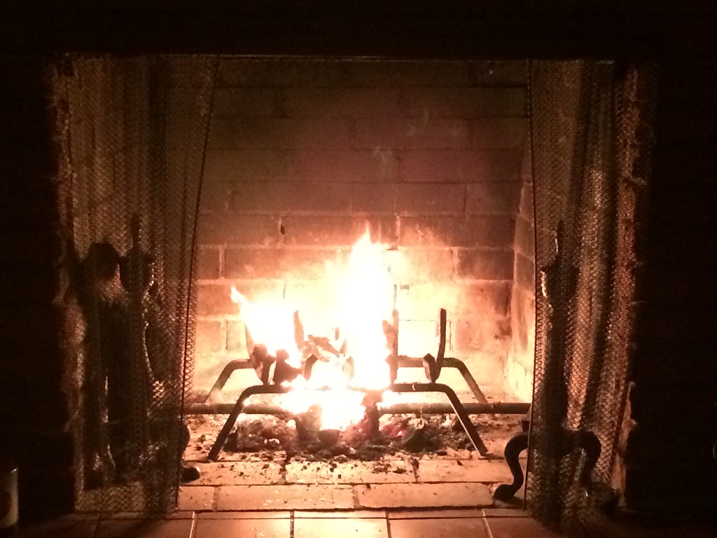 A brick fireplace with fire and grate