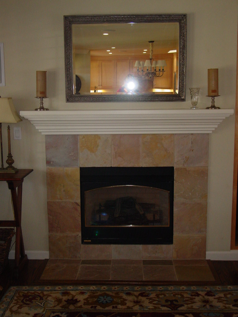 An installed gas fireplace with a stone surround and mantel