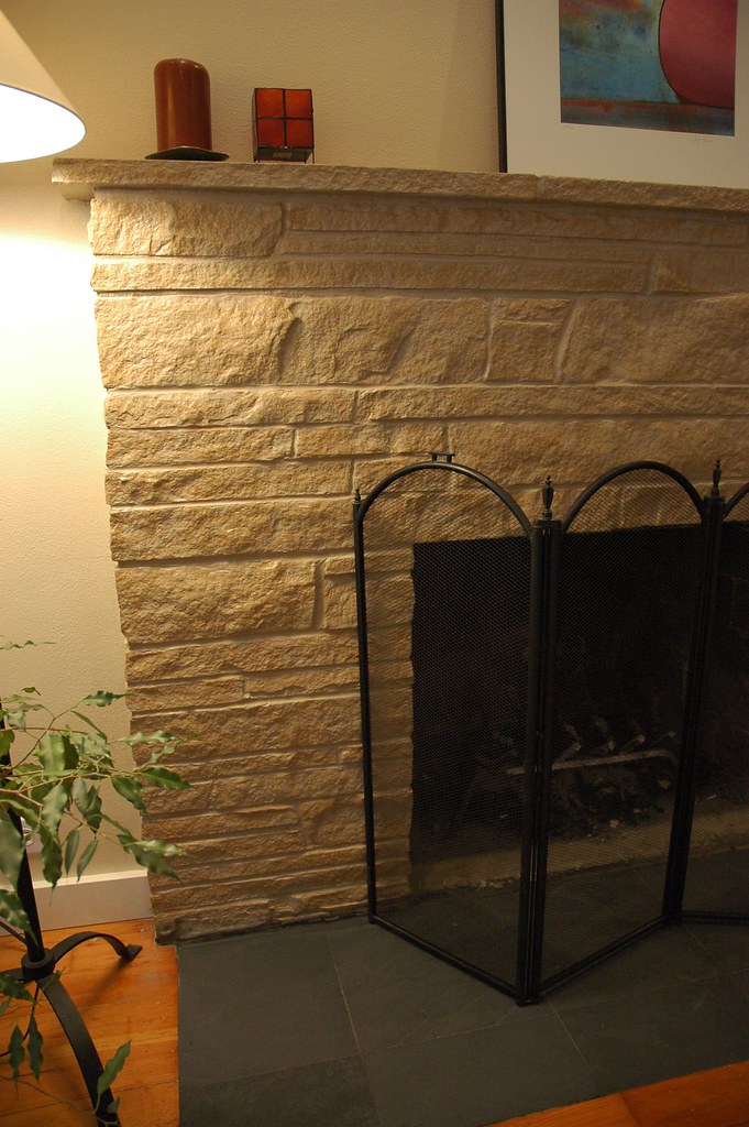 A stone fireplace with mantel and a fire screen