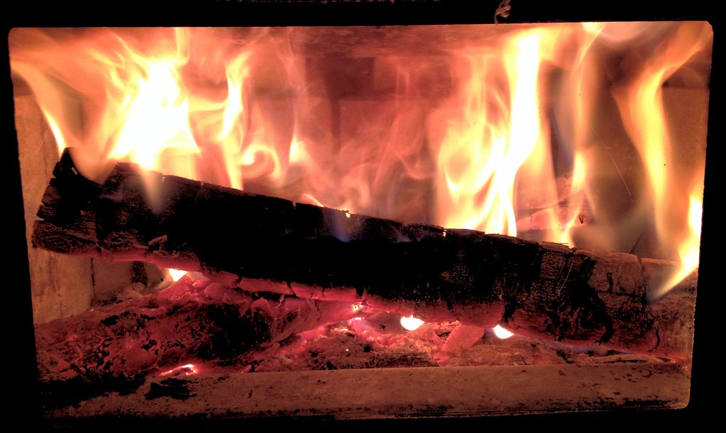 A glowing log fire behind glass