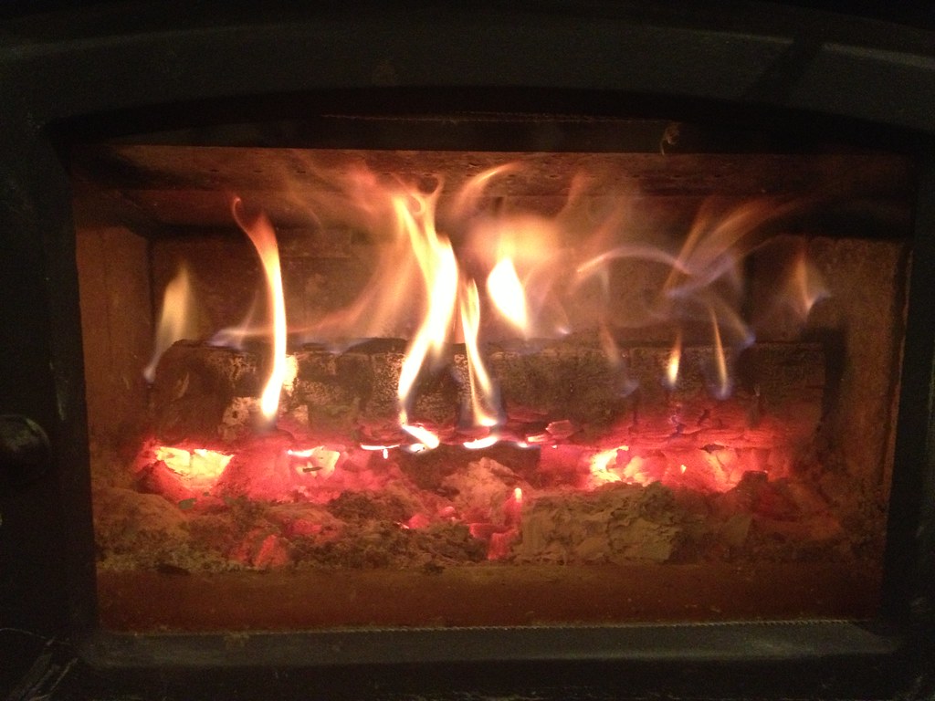 Flames over a log set behind glass