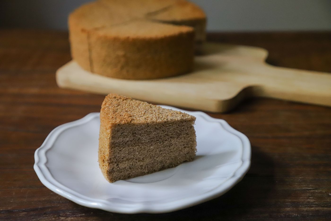 A plain sponge cake with a cut slice on a plate