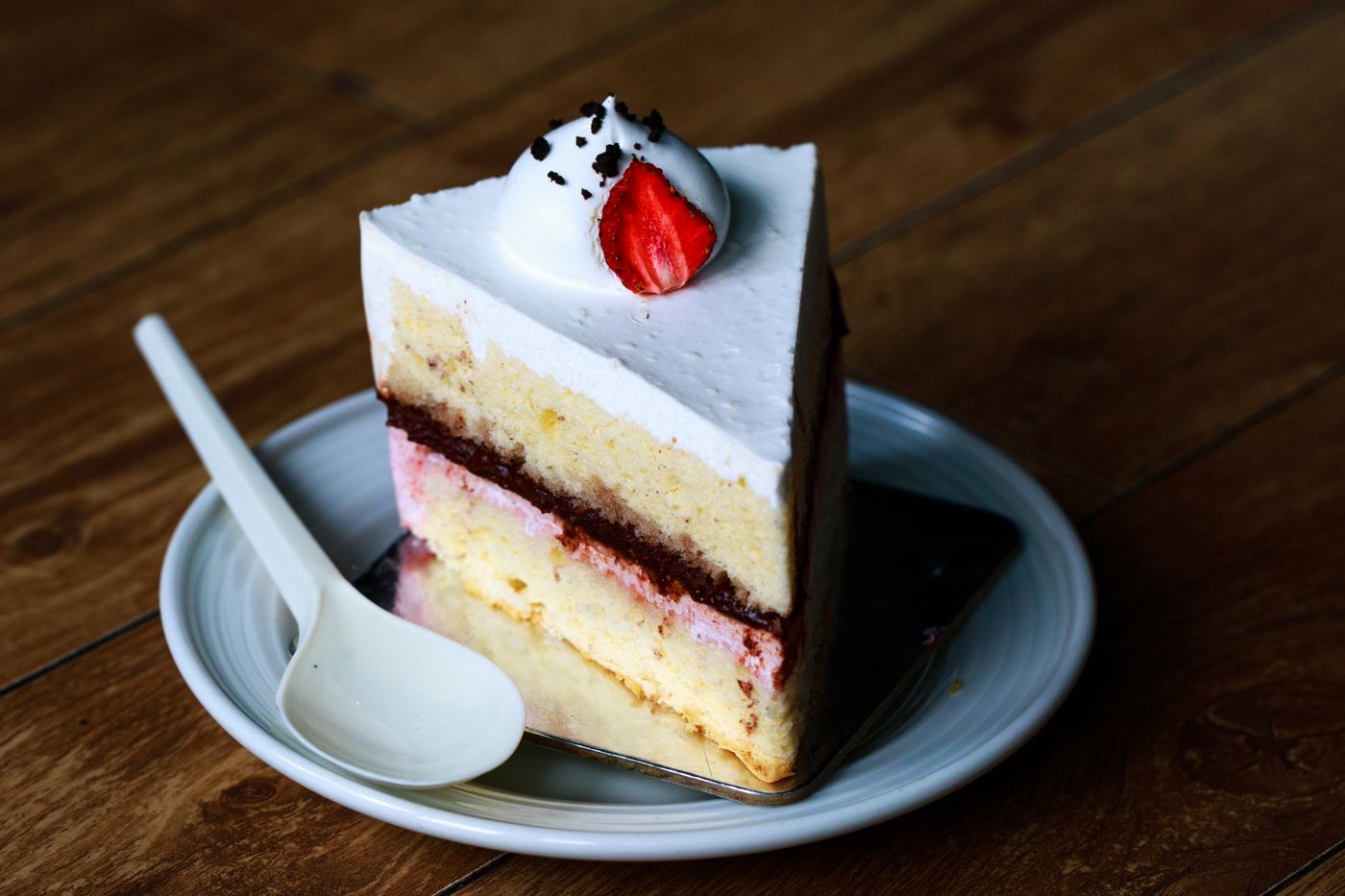 A layered cake slice topped with whipped cream and a fresh strawberry