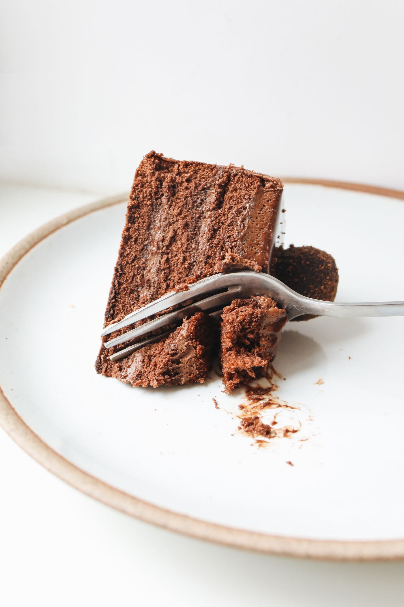 A slice of chocolate layer cake on a plate with a fork