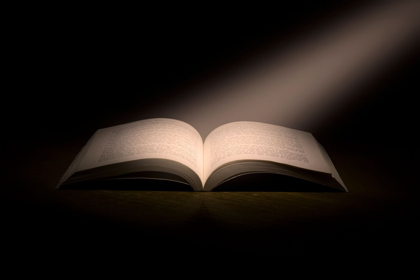 An open book lit dramatically against the dark