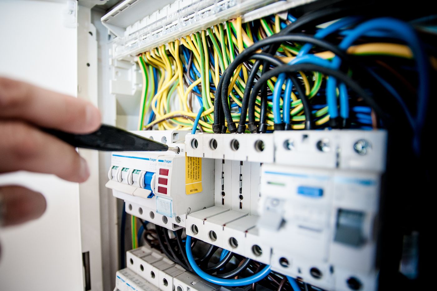 A hand working at an open breaker panel during a service call