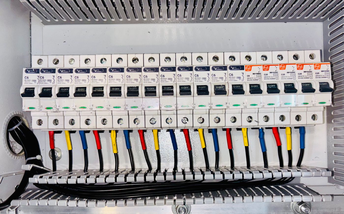A neatly wired residential breaker panel with colour-coded conductors