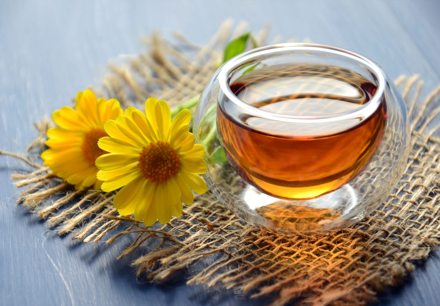 A glass of amber tea on a woven mat