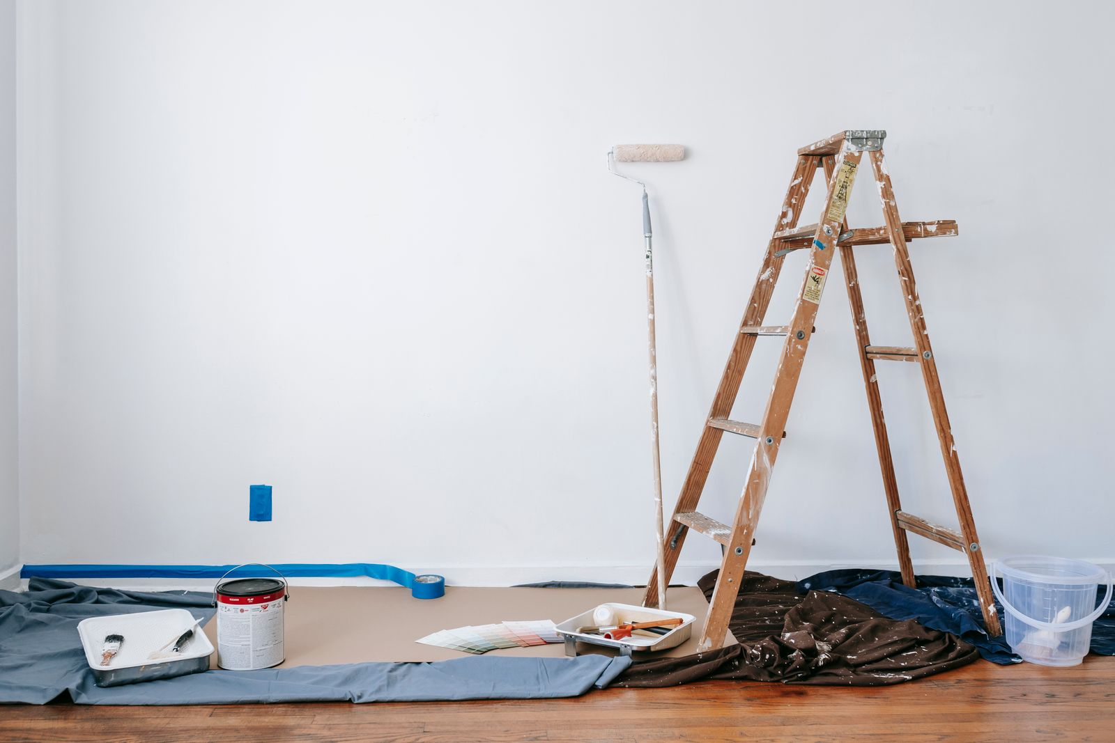 A ladder and drop cloth set up in a room being painted