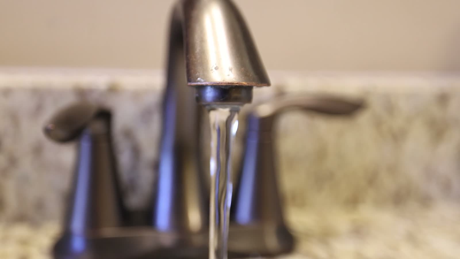 Water running from a bathroom faucet into a sink